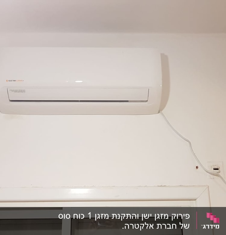 מזגן קיר לבן מותקן מעל חלון עם כבל חשמל